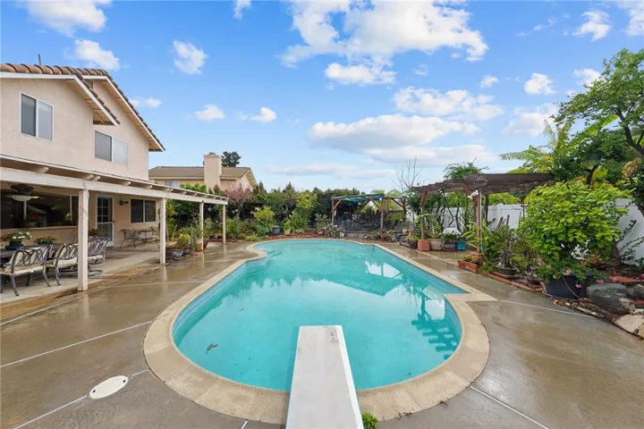Sparkling in-ground pool with generous deck space, mature landscaping, and covered patio for entertaining.