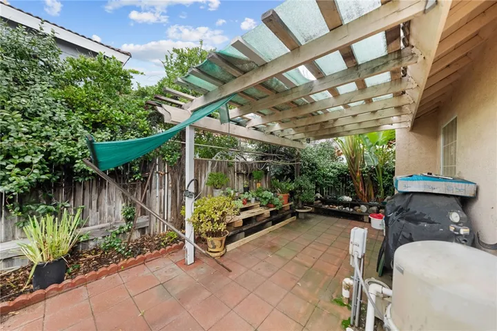 Sheltered patio area with paver flooring and space for storage/workbench/potting, offering functional outdoor flex space.
