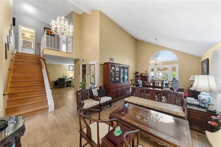 Open layout connecting living and dining areas with high ceilings, wide-plank style flooring, and bright windows throughout.