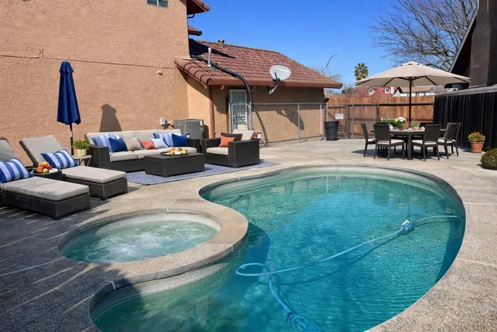 Combined pool / hot tub with a patio and an outdoor living / dining area
