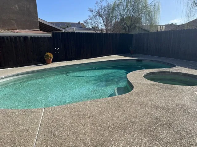 View of pool featuring a fenced backyard, an in-ground hot tub, and patio surround