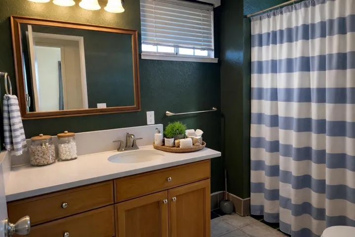 Full bath with a textured wall, vanity, a shower with shower curtain, and light tile patterned flooring