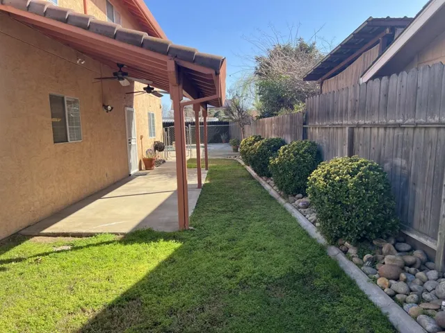 Fenced backyard featuring a ceiling fan and a patio