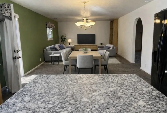 Dining area with arched walkways, suspended lighting, and dark carpet