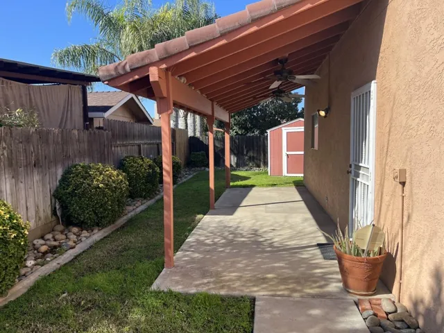 Fenced backyard featuring a shed and ceiling fan
