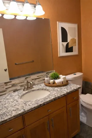 Bathroom featuring a textured wall, vanity, and decorative backsplash