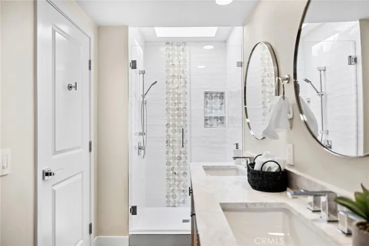 Primary bathroom with double vanity, walk-in shower and skylight