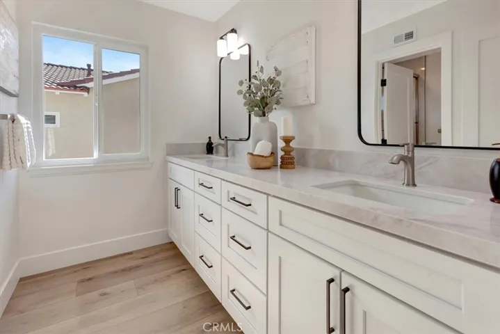 Upstairs hall bath features white shaker cabinetry, dual vanity, Ivory Taj quartz countertop &, framed mirrors.
