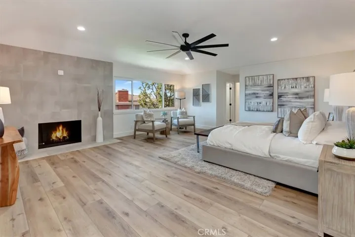 Upstairs, a custom iron staircase leads to four spacious bedrooms, including a luxurious primary suite with double door entry, coffered ceilings, a dramatic floor-to-ceiling tiled fireplace