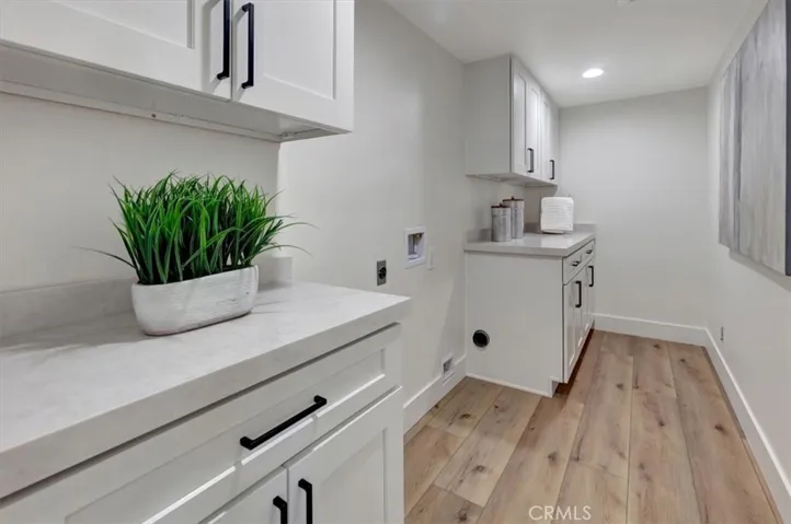 Convenient inside laundry room with white shaker cabinetry & Ivory Taj quartz countertops.