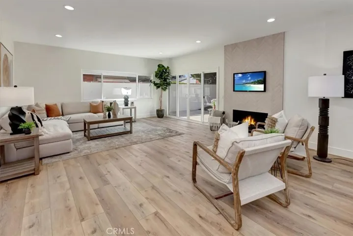 The rear of the home unfolds into an open-concept kitchen, dining, and huge family room highlighted by a stunning floor-to-ceiling fireplace and expansive sliding doors that invite indoor-outdoor living.