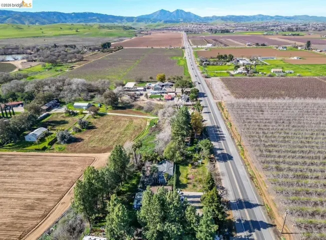 Aerial view of sparsely populated area featuring large plots for crops and a mountain backdrop
