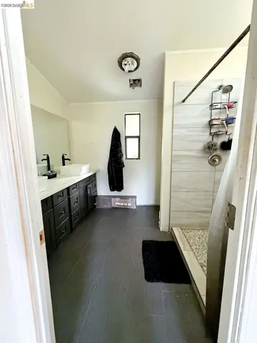 Full bathroom with a shower stall, double vanity, and lofted ceiling