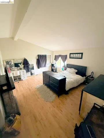 Bedroom with beamed ceiling and wood finished floors