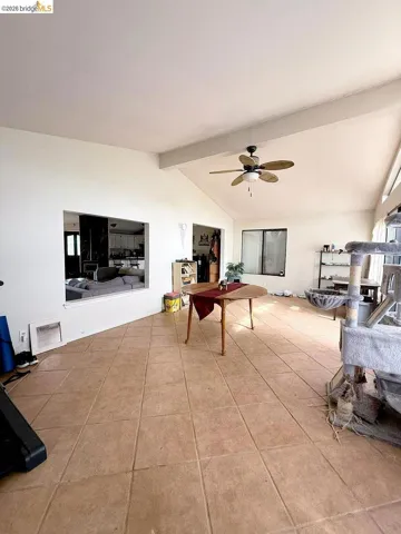 Living room with a ceiling fan, beam ceiling, and light tile patterned floors