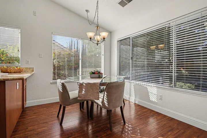 Dining space featuring a textured wall, lofted ceiling, a chandelier, and dark wood-style floors