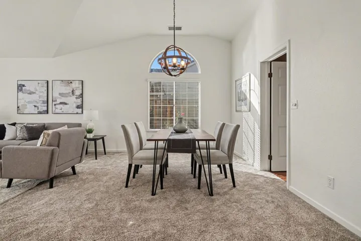 Dining area with light carpet, lofted ceiling, and suspended lighting