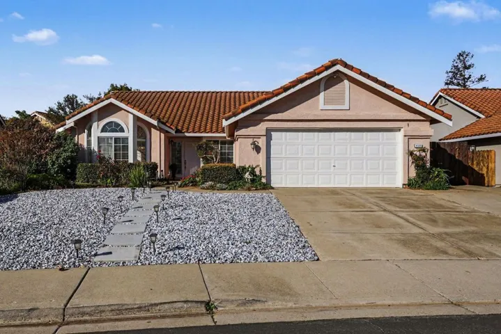Mediterranean / spanish-style house with stucco siding, driveway, a tiled roof, and a garage