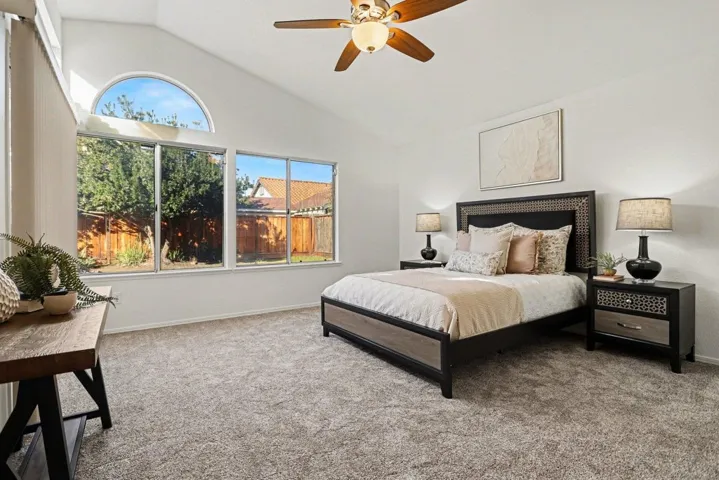 Carpeted bedroom with lofted ceiling and ceiling fan
