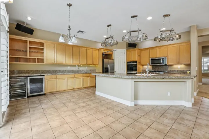Kitchen featuring open shelves, wine cooler, stainless steel appliances, and light wood finish cabinets