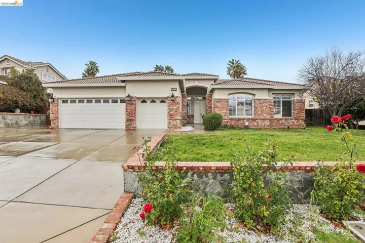 View of front of property featuring stucco siding, a garage, a tiled roof, and concrete driveway