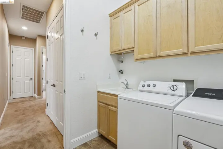 Laundry area featuring cabinet space, light colored carpet, and washing machine and dryer