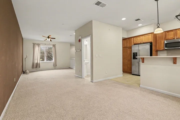 Kitchen featuring wood finish cabinets, stainless steel appliances, light colored carpet, open floor plan, and light countertops