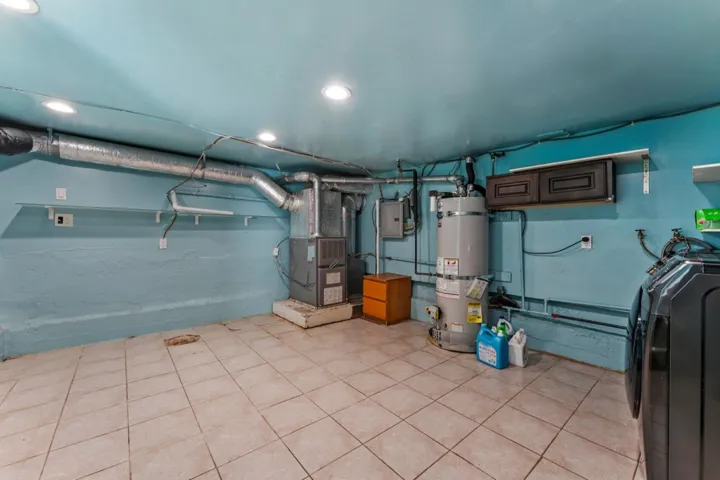 Utility room featuring washer / dryer, strapped water heater, electric panel, and heating unit