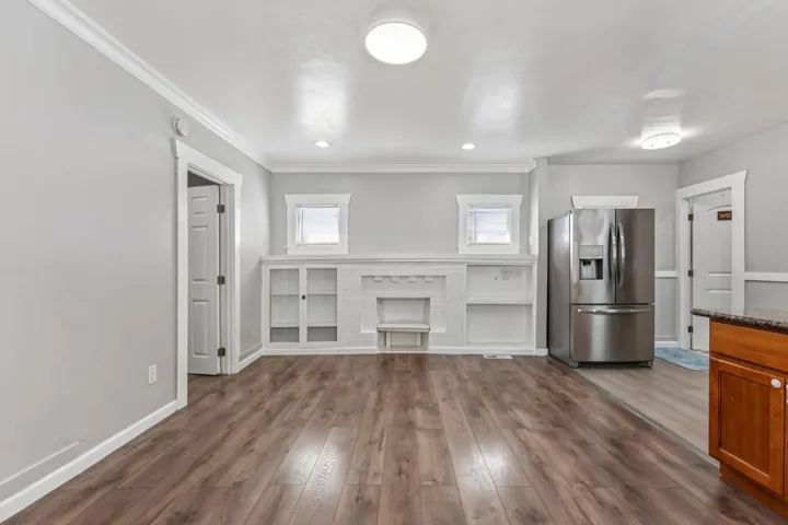 Unfurnished living room with dark wood-type flooring, ornamental molding, and recessed lighting