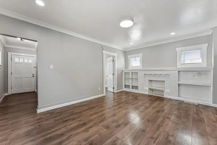 Unfurnished living room featuring crown molding, dark wood-style floors, and recessed lighting