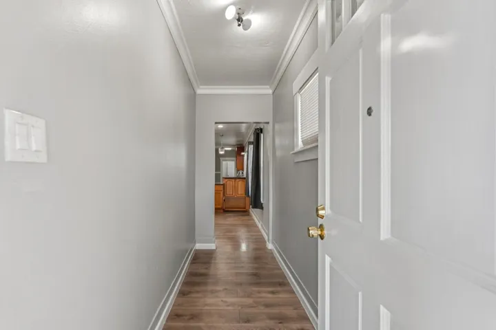 Hallway featuring ornamental molding and dark wood-type flooring