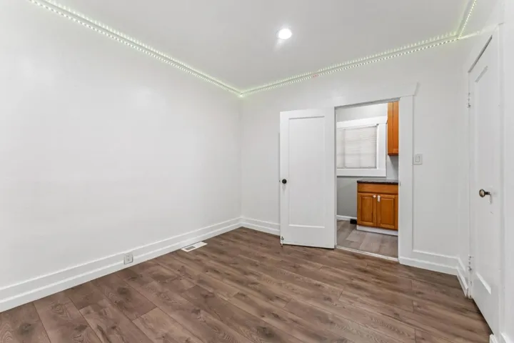 Unfurnished bedroom with dark wood-style flooring and baseboards