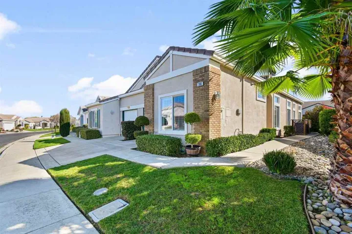 View of side of home with stucco siding, a lawn, brick siding, and a residential view