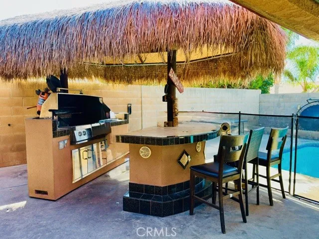 Built-in BBQ with Palapa on top of Island-Digitally Enhanced, chair, phone charger, & clutter removed