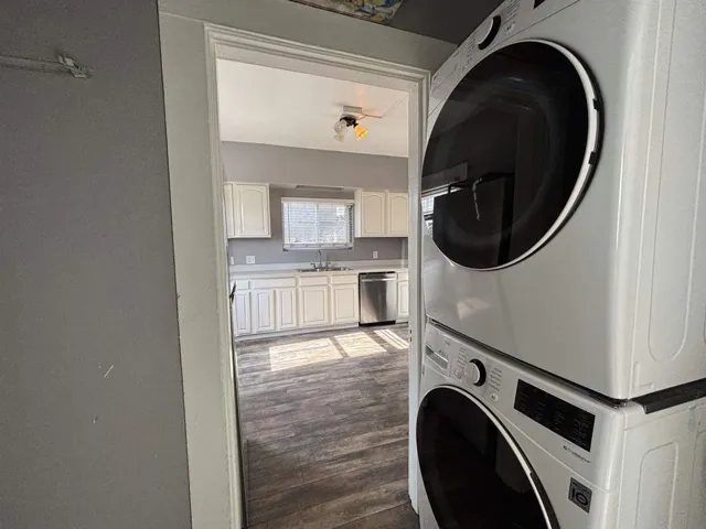 Laundry area featuring dark wood-style floors and stacked washer / drying machine