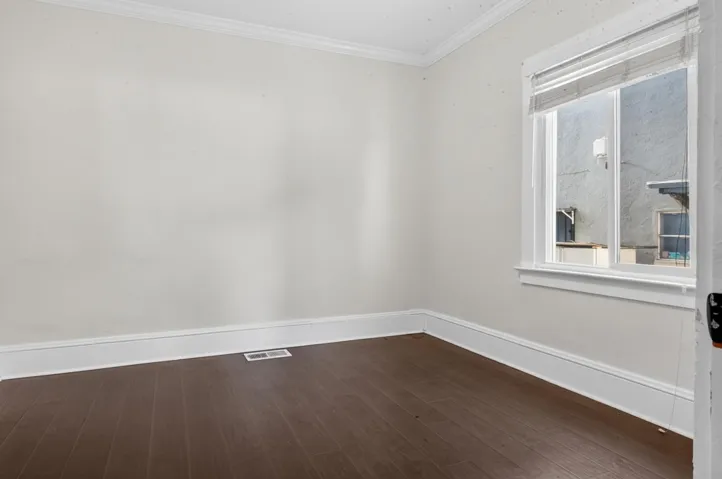 Unfurnished room with crown molding and dark wood finished floors