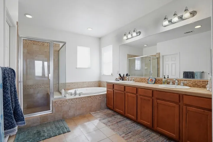 Bathroom with a shower stall, double vanity, light tile patterned floors, a bath, and recessed lighting