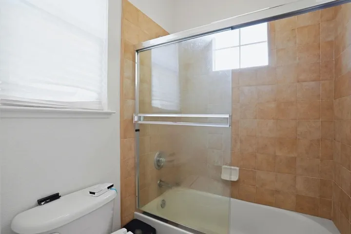 Full bathroom with shower / bath combination with glass door and toilet