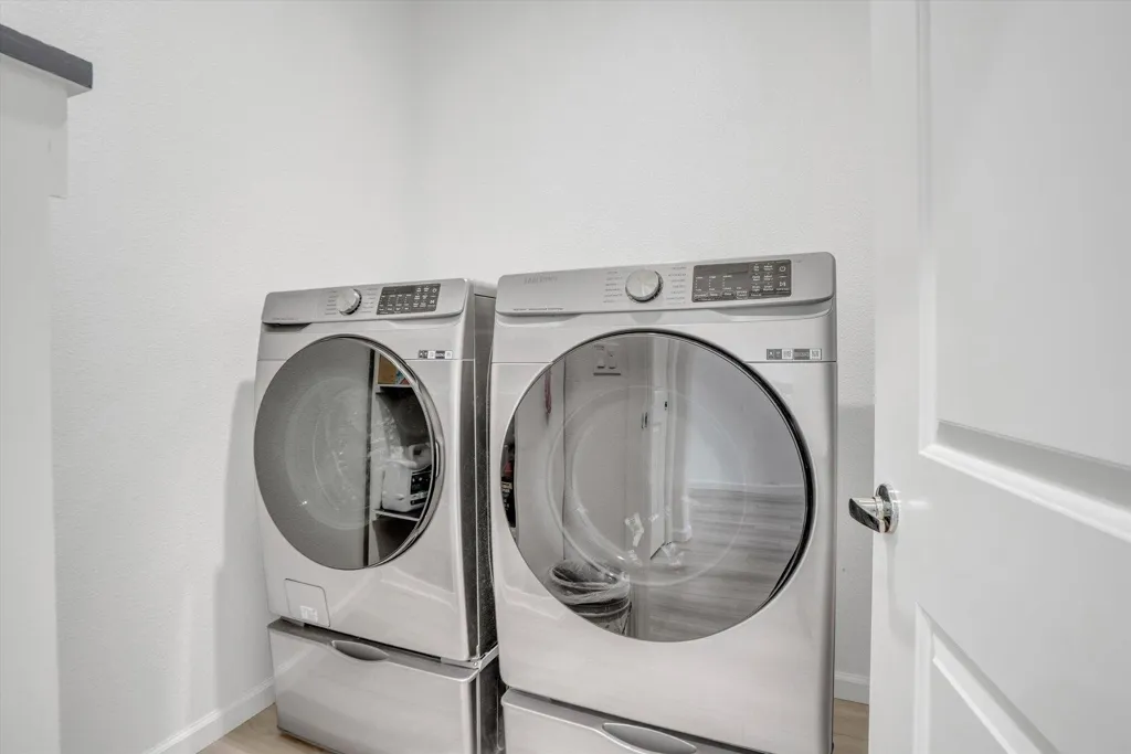 laundry area with independent washer and dryer and light wood finished floors