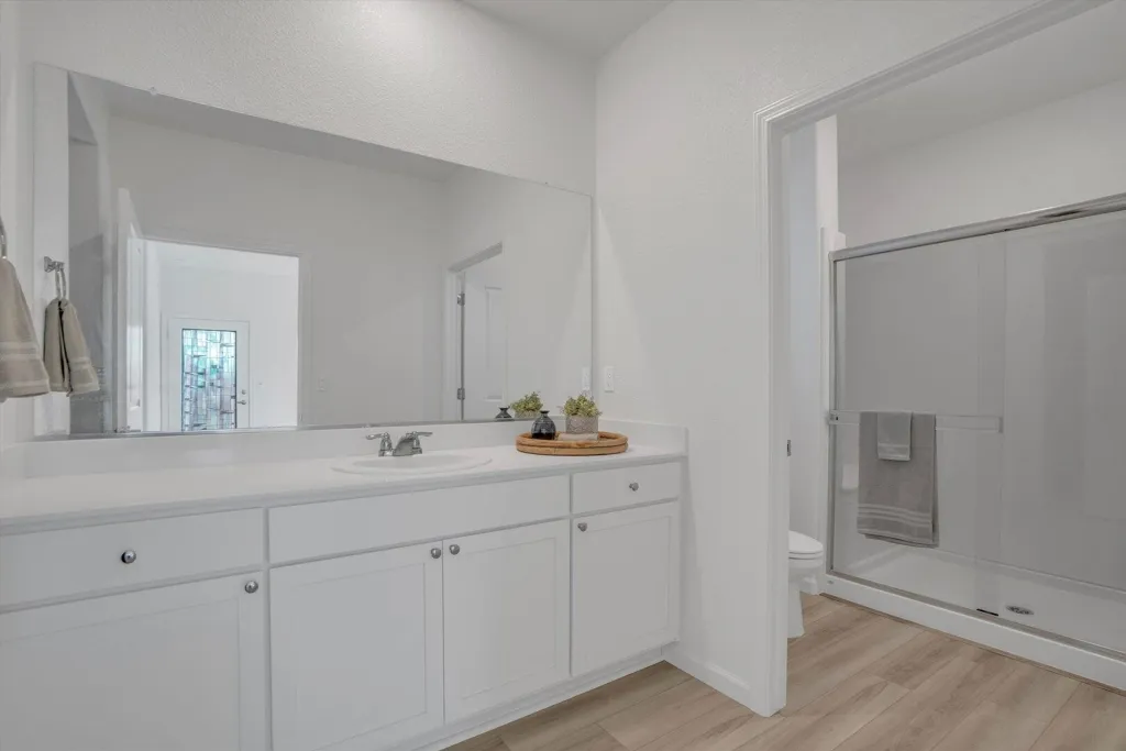 full bathroom featuring vanity, a shower stall, and light wood finished floors