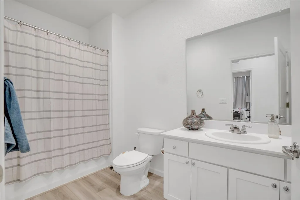bathroom with vanity, shower / bath combo with shower curtain, and light wood-style flooring