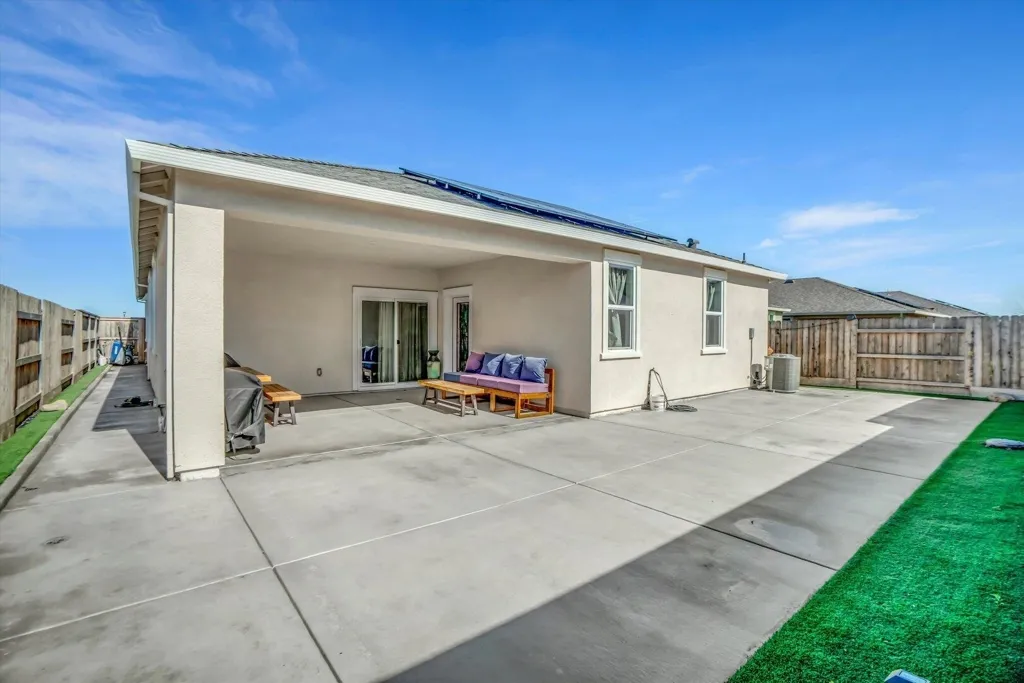 back of property featuring a fenced backyard, solar panels, stucco siding, a patio area, and an outdoor hangout area