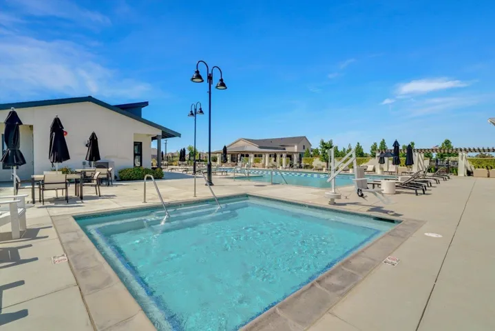 community pool with a patio area and a community hot tub