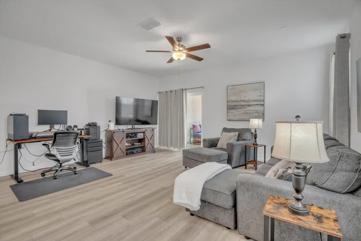 living area featuring an office area, light wood-style floors, and a ceiling fan