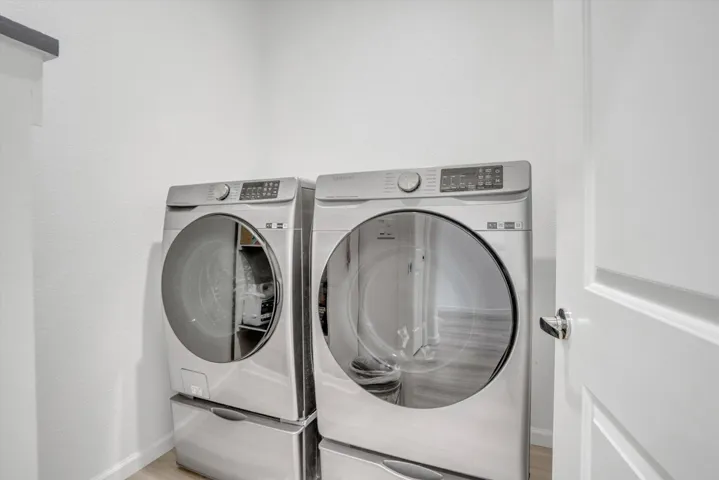 laundry area with independent washer and dryer and light wood finished floors