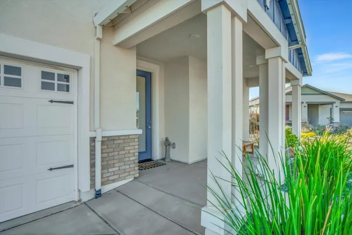 entrance to property featuring a garage, stucco siding, and stone siding