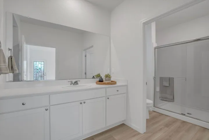 full bathroom featuring vanity, a shower stall, and light wood finished floors