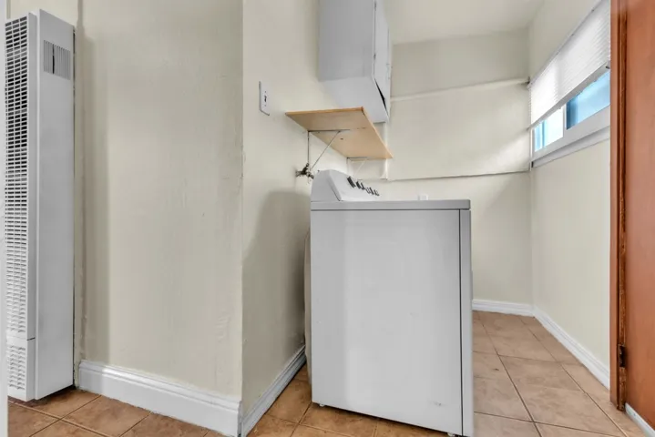 Laundry room featuring a heating unit, washer / clothes dryer, and light tile patterned floors