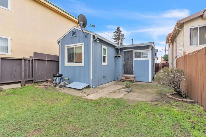 Rear view of house with a fenced backyard and a patio area