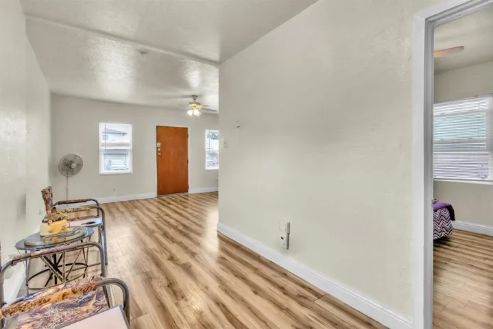 Entryway featuring light wood-type flooring, a ceiling fan, a textured ceiling, and a textured wall
